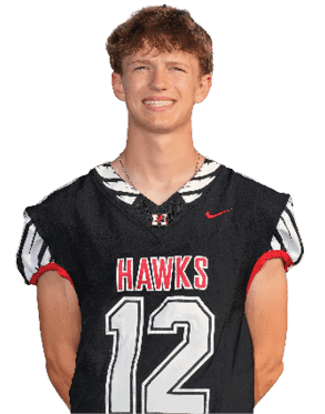 A person with short curly hair is smiling and wearing a black sports jersey with red and white accents that says “HAWKS" and the number 12. Description generated by AI