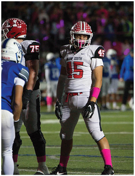 A person wearing a football helmet with red and white stripes and stars is on a field with a blurred crowd in the background. Description generated by AI