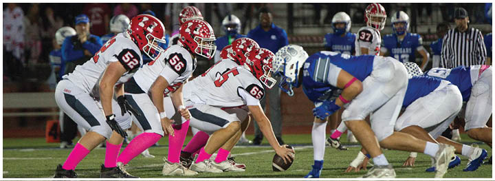 Two opposing American football teams are lined up facing each other on the field, ready for the next play. Description generated by AI