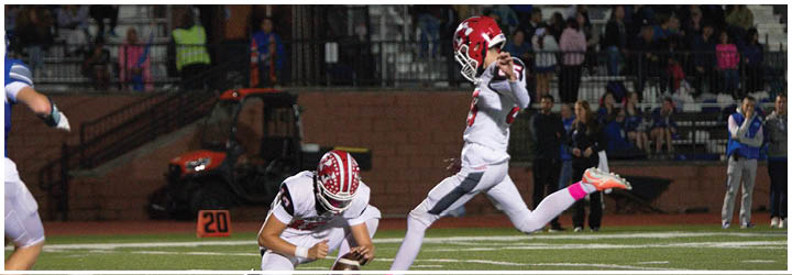 A person in a white and red football uniform is jumping or reaching up on a football field with spectators in the background. Description generated by AI