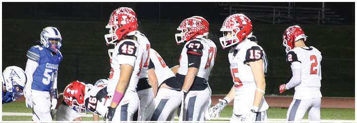 Several people in football uniforms are lined up on a field, preparing for a play. Description generated by AI
