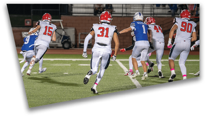 Several people wearing football uniforms are actively running on a field during a game, with some players in white and red and others in blue and white. Description generated by AI