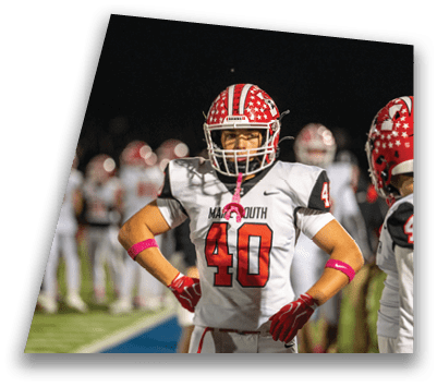A person wearing a red and white football uniform with the number 40 stands on a field with hands on hips while another person in a similar uniform with the number 4 faces them. Description generated by AI