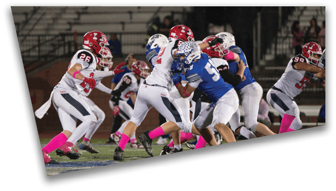 People wearing football uniforms and pink socks are engaged in a play on a football field during a game. Description generated by AI