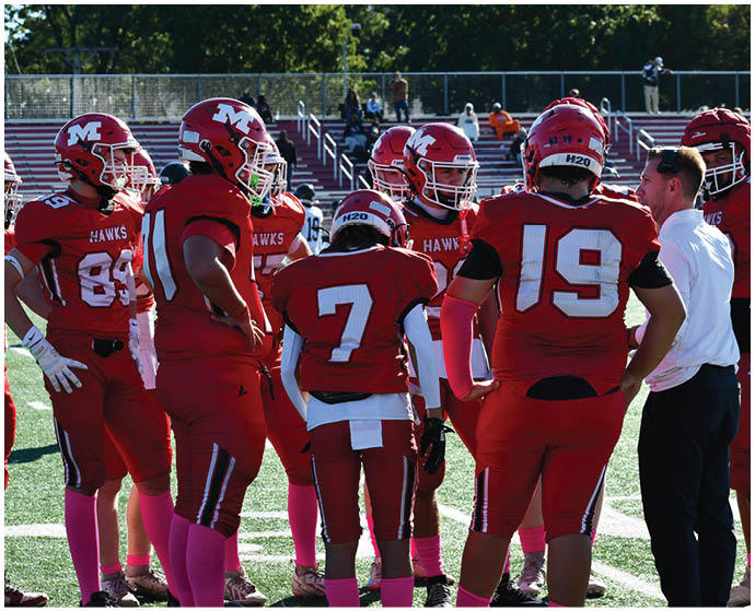 A group of people wearing red football uniforms with pink socks are standing together on a football field. Description generated by AI