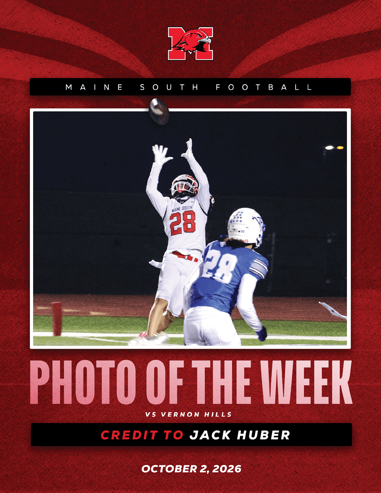 A person in a white football uniform with the number 28 is reaching up to catch a football while another person in a blue uniform with the number 28 watches during a night game. Description generated by AI
