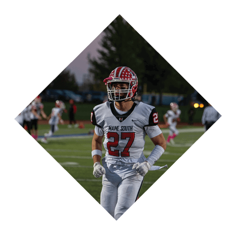 A person wearing a white football uniform with the number 27 is running on a football field during a game. Description generated by AI