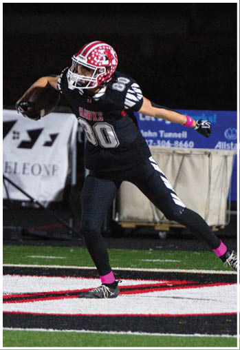 A person wearing a football uniform with a red and white helmet is running on a field with a black, white, and red logo. Description generated by AI