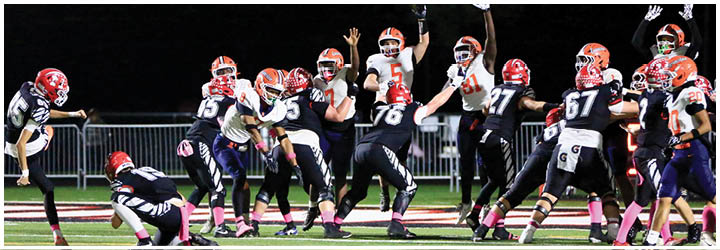 A group of football players in black and white uniforms are celebrating on the field while one player in a red helmet is kicking the ball. Description generated by AI