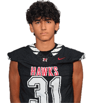 A person with curly hair is standing with hands behind their back wearing a black football uniform with the word “HAWKS" and the number 31 on the front. Description generated by AI