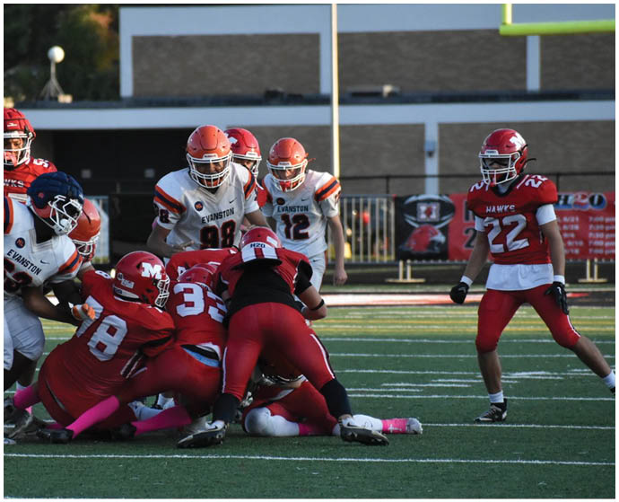 A group of people wearing football uniforms are engaged in a play on a football field with some players in red and others in white and orange jerseys. Description generated by AI