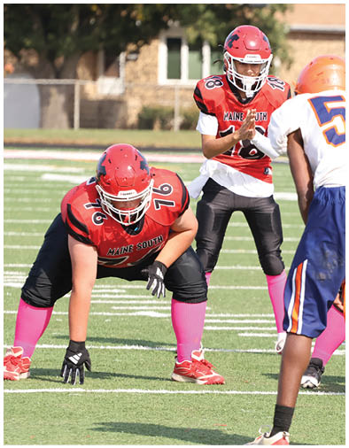 Several people in football uniforms are positioned on a field, appearing to prepare for a play during a game. Description generated by AI