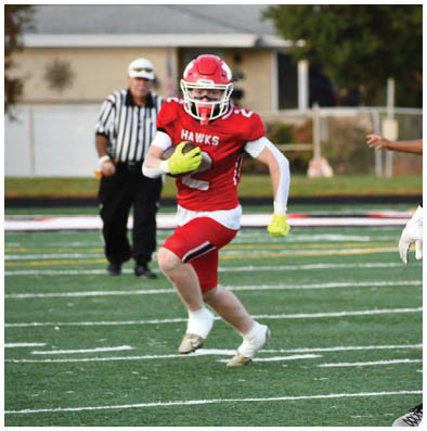 People wearing sports uniforms and gloves are running on a green football field with white yard lines. Description generated by AI