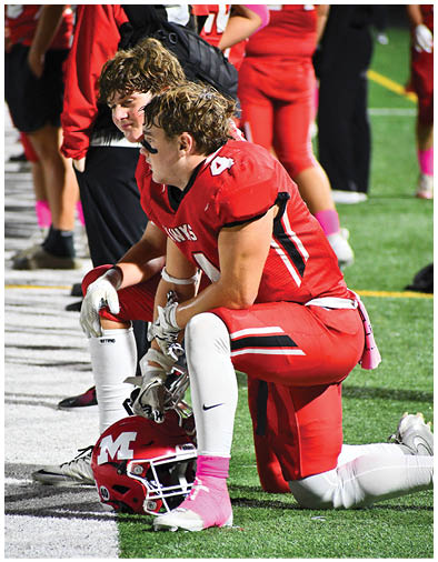 Two people with wet hair wearing red sports uniforms appear focused and engaged, likely during a sports event. Description generated by AI