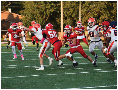 People wearing red and white football uniforms are actively playing on a green field during a game. Description generated by AI