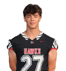 A person with short hair is standing with hands behind their back wearing a black sports jersey with the word “HAWKS" and the number 27 on the front. Description generated by AI