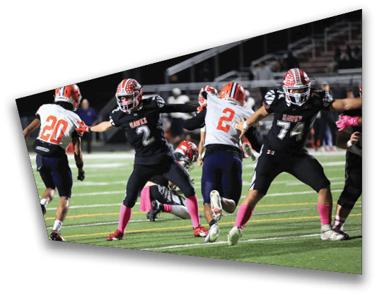 Two people in football uniforms are on a field with one person lying on the ground and the other standing nearby. Description generated by AI