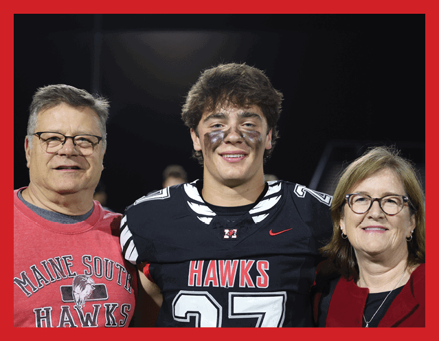 Three people stand close together with one wearing a black football jersey with the number 27 and the word Hawks while another wears a red sweatshirt with Maine South Hawks printed on it. Description generated by AI