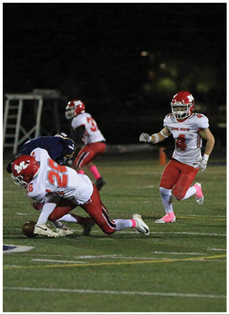 Two people in football uniforms are on a field with one person tackling the other who is holding the football. Description generated by AI