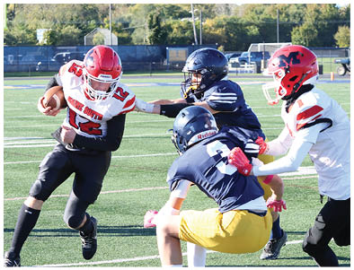 A person wearing a red helmet and white football jersey with the number 12 is running with a football while two people in dark helmets and jerseys attempt to block or tackle them on a football field. Description generated by AI
