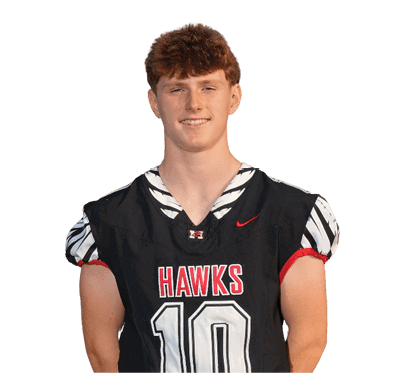 A person with short curly hair is wearing a black sports jersey with the word “HAWKS" and the number 10 on the front, standing against a white background. Description generated by AI
