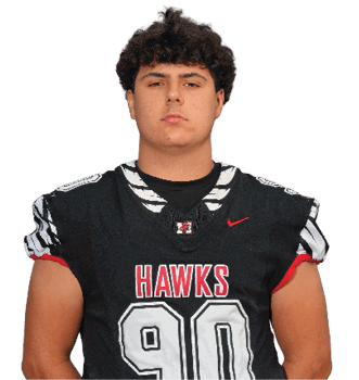 A person with curly hair wearing a black football jersey with the word “HAWKS" and the number 90 stands facing forward against a white background. Description generated by AI