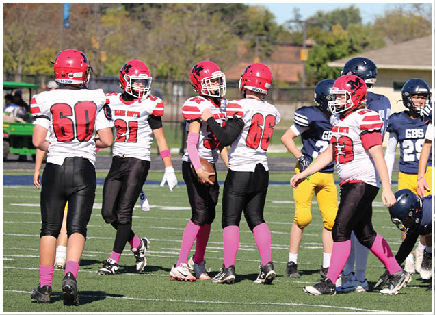 Several people wearing football uniforms in red, white, black, and yellow are gathered on a field during a game or practice. Description generated by AI
