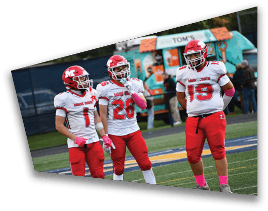 Three people wearing red and white football uniforms with helmets stand on a sports field during a game. Description generated by AI