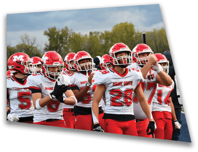 A group of people wearing red and white football uniforms and helmets are gathered closely together outdoors, appearing energetic and focused. Description generated by AI