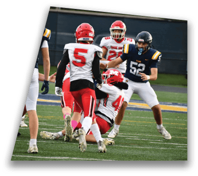 Several people in football uniforms are engaged in a play on a grassy field with one person on the ground and others standing nearby. Description generated by AI
