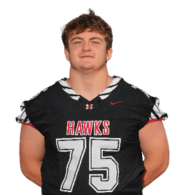 A person wearing a black football jersey with the word “HAWKS" and the number 75 stands with hands behind their back against a white background. Description generated by AI