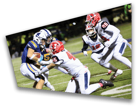 People in football uniforms are actively engaged in a play on a grassy field during a game. Description generated by AI