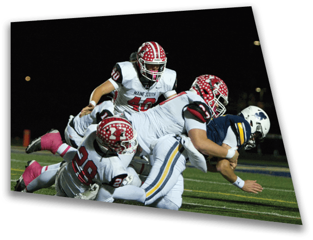 Several people wearing football helmets and uniforms are engaged in a play on a football field at night. Description generated by AI