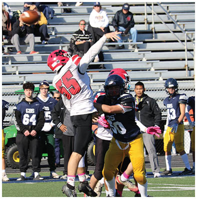 A group of people in football uniforms are on a field with one person in a white and red jersey jumping to catch a football while others watch or prepare to engage. Description generated by AI