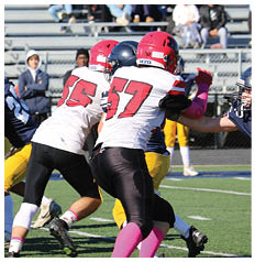 Several people wearing football helmets and uniforms are engaged in a play on a football field. Description generated by AI