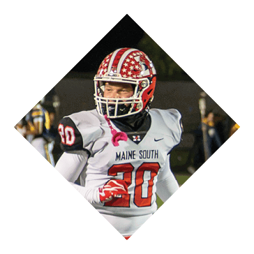 A person wearing a red and white football helmet and a white jersey with the number 30 is on a football field at night with other players in the background. Description generated by AI