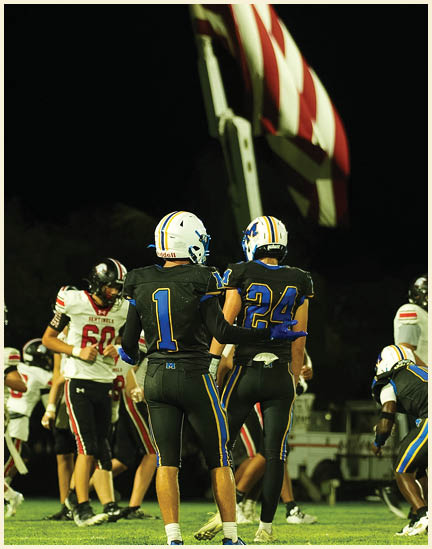 A football player wearing a black jersey with the number 11 on it. Description generated by AI