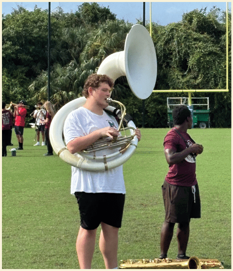 Three men wearing green and white uniforms are standing on a field. Description generated by AI