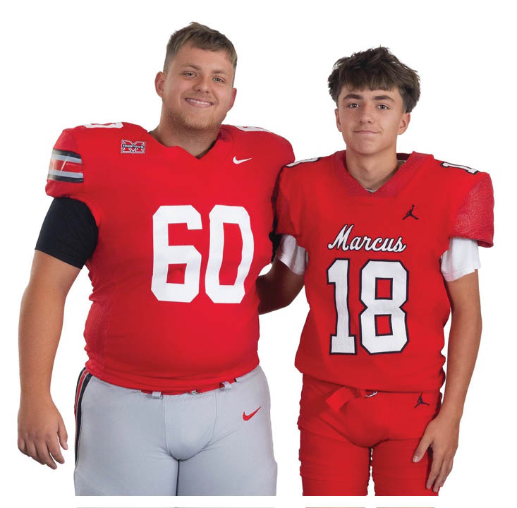 Two people wearing red football uniforms with numbers 60 and 18 stand side by side smiling. Description generated by AI