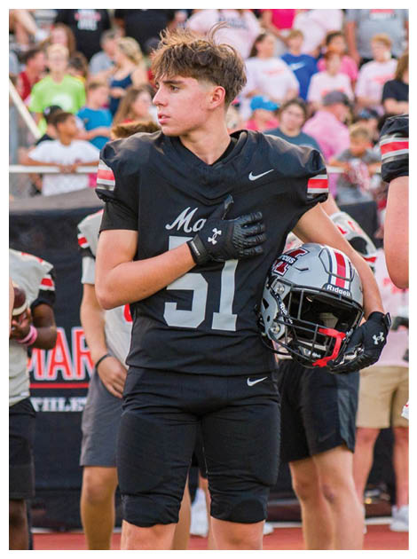 Two football players wearing black jerseys and holding hands. Description generated by AI
