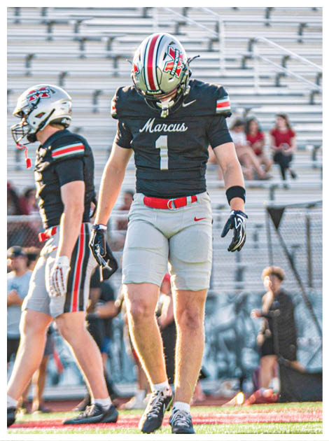 Two football players wearing black jerseys and holding hands. Description generated by AI