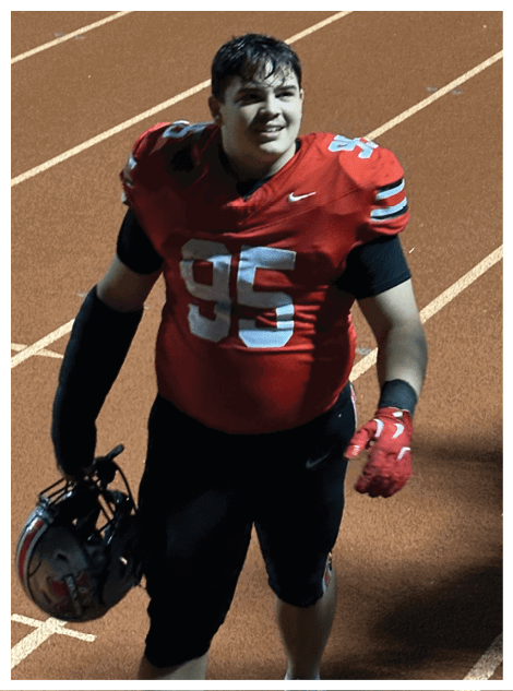 Two football players wearing black jerseys and holding hands. Description generated by AI