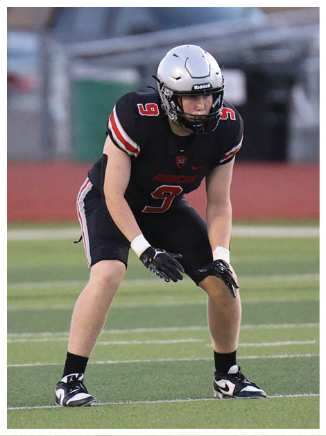 Two football players wearing black jerseys and holding hands. Description generated by AI