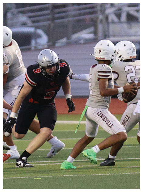 Two football players wearing black jerseys and holding hands. Description generated by AI