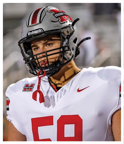 A person wearing a white football jersey with red numbers and a silver helmet with a red and black logo is looking to the side on a blurred outdoor field. Description generated by AI