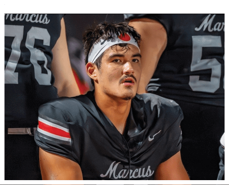 Two football players wearing black jerseys and holding hands. Description generated by AI