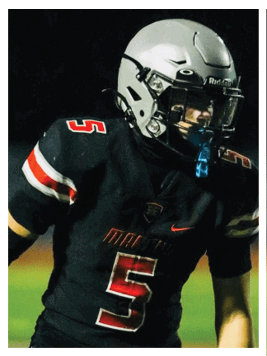 Person wearing a gray football helmet and black sports jersey with red and white numbers, looking to the side. Description generated by AI