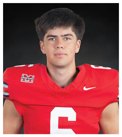 A person with short dark hair is wearing a red sports jersey against a dark background. Description generated by AI