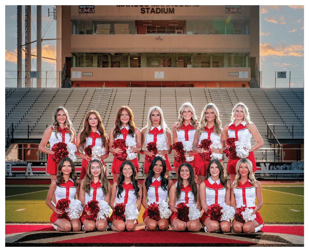 A group of cheerleaders pose for a photo in front of a stadium. AI generated content