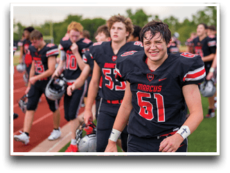 Three football players are standing on the field, one of them is smiling and wearing a black jersey with the number 55. AI generated content